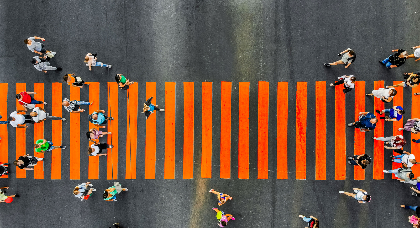 peolpe walking on an orange pedestrian crossing viewed from above